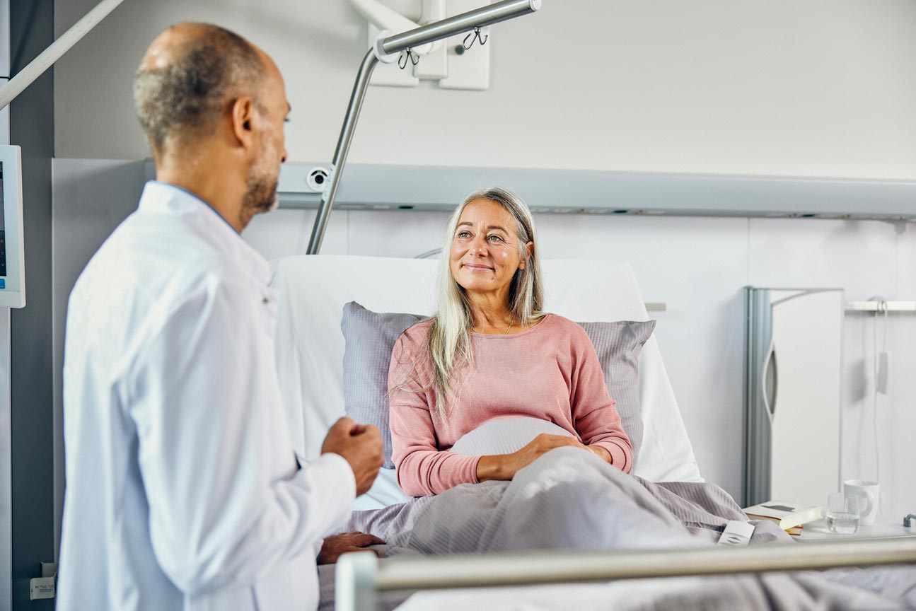 Surgeon and patient in hospital bedroom